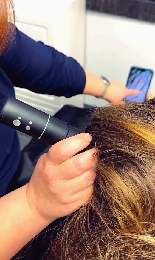 Cheree looking at a guest's scalp with a dermascope to determine what products to use.